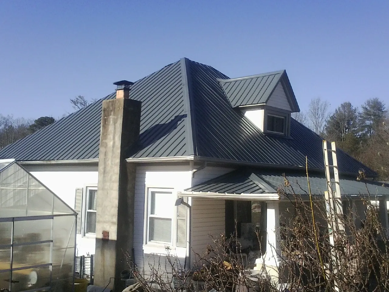 Dark blue standing seam metal roof on a white farmhouse with dormer — Slate & Tile Roof Repair by Roofing Brothers in Spreckels
