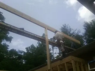 Carpenter setting a ridge beam over a new addition frame — Ice Dam Removal by Roofing Brothers in Spreckels