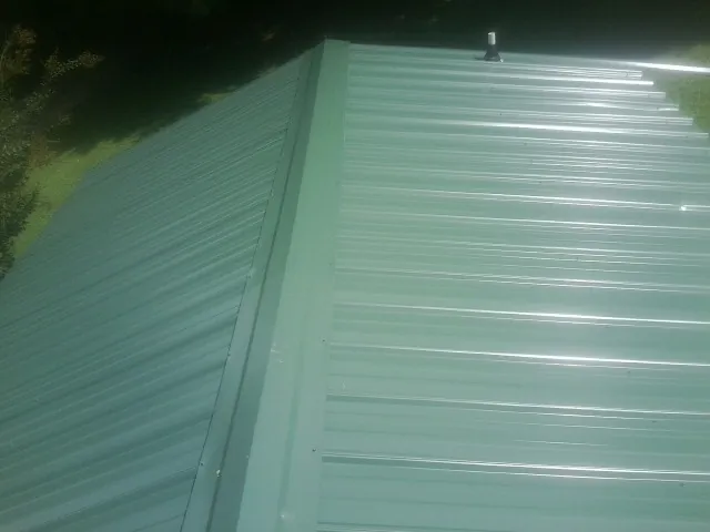 New green metal panels meeting at the ridge of a roof — Flat Roof Repair work by our crew in Spreckels