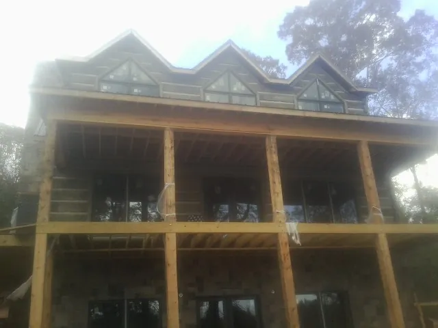 Dormers and porch framing on a large log home under construction — Roof Coating work by our crew in Spreckels