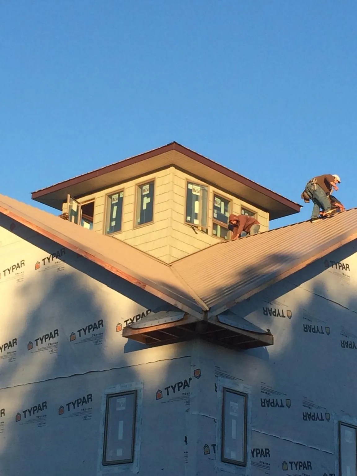 Roofers working around a rooftop cupola on a new metal roof at sunset — Roof Waterproofing in Spreckels by Roofing Brothers